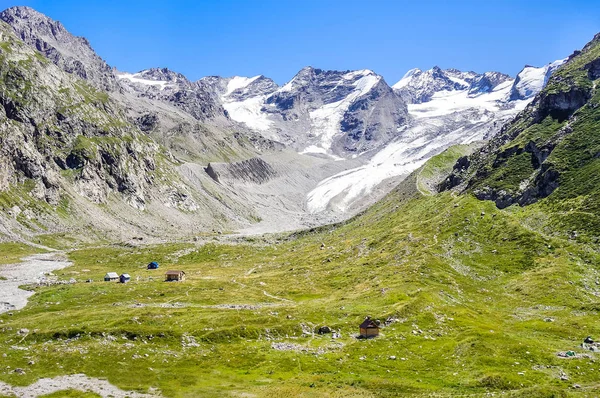 Houses in the valley at the foot of snow-capped mountains — Stock Photo, Image