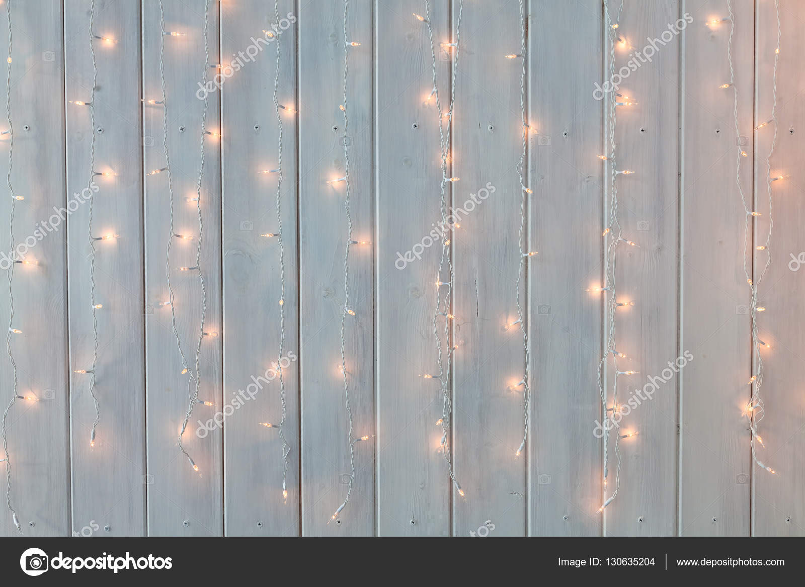 Christmas lights burning on a white wooden background. New Year back