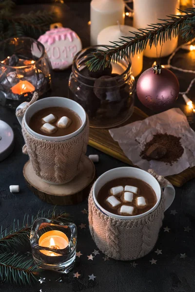 To kopper i strikkede vanter av fersk varm kakao eller sjokolade på julaften av tre, mørk foto – stockfoto