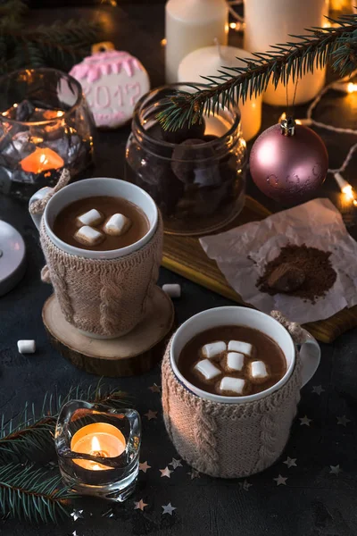 Two cups in knitted mittens of fresh hot cocoa or chocolate on wooden christmas background, dark photo — Stock Photo, Image