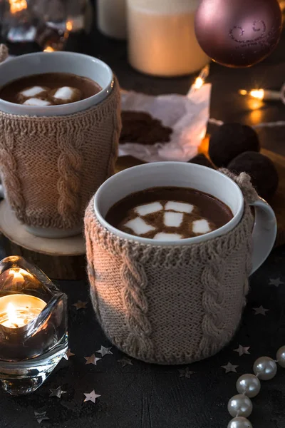 Two cups in knitted mittens of fresh hot cocoa or chocolate on wooden christmas background, dark photo — Stock Photo, Image