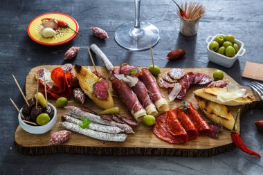 Farklı aperatifler ve mezeler karışımı. İspanyolca tapas siyah bir taş zemin üzerine. Bar. Metin için yer. Şarküteri, sandviç, zeytin, sosis, hamsi, peynir, jamon, biber, domates. Üstten Görünüm