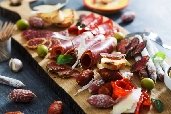 Geleneksel İspanyolca tapas - chorizo, salsichon, jamon serrano, lomo - erved zeytin ve ekmek ile ahşap tahta üzerinde tedavi et tabağı