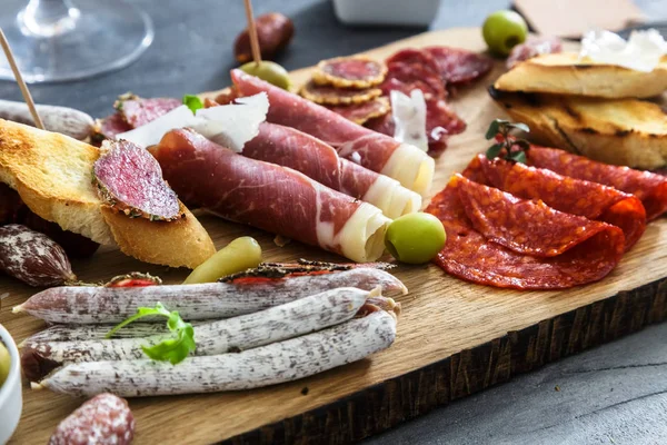 Geleneksel İspanyolca tapas - chorizo, salsichon, jamon serrano, lomo - erved zeytin ve ekmek ile ahşap tahta üzerinde tedavi et tabağı