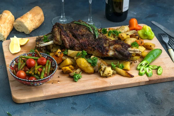 Gebraden schouder van lam op gebakken aardappelen en wortelen, houten plank, bovenaanzicht — Stockfoto