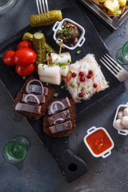 Geleneksel atıştırmalık sebze, soğan, domuz yağı, ekmek, patates ve iki kadeh votka ile ringa balığı tuzlu.
