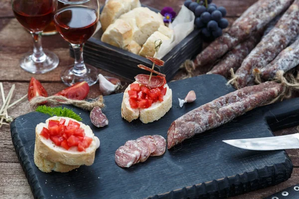 Pane affettato, pomodoro e salsiccia per bruschette su tagliere di legno — Foto Stock