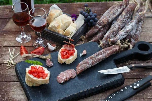 Pane affettato, pomodoro e salsiccia per bruschette su tagliere di legno — Foto Stock