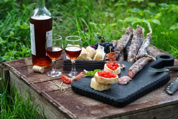 Bruschetta, rebanadas de baguette decoradas con ajo, tomate y salchicha, se cierran sobre una tabla de madera — Foto de Stock