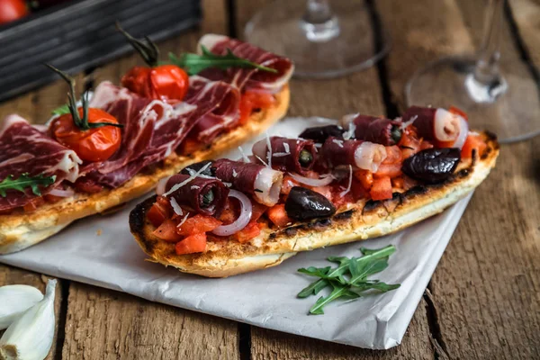 Set de aperitivos de vino. Copa de vino tinto, pinceles con tomate fresco y jamón sobre fondo de madera grunge rústico — Foto de Stock