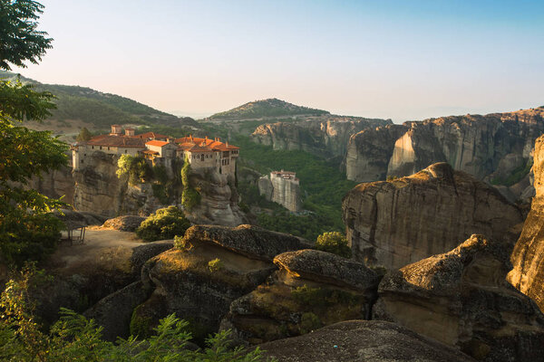 Первые солнечные лучи на Свято-Варлаамском монастыре на краю высокой скалы. Каламбака, Греция
