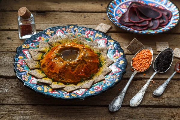 Hummus casero con ruscos, ternera curada y especias en mesa rústica . —  Fotos de Stock