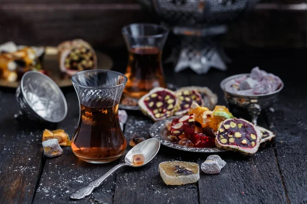 Thé turc avec des tasses en verre authentiques. Deux tasses de thé turc et des bonbons sur fond de bois sombre — Photo