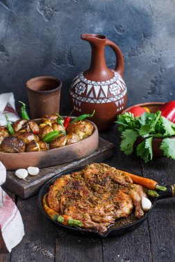 Bütün kızarmış tavuk fırında patates ve şarap ile bir demir tavada. Gürcü tapaka tavuk. Koyu arka plan