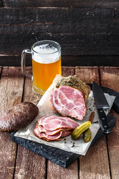 Smoked ham with rye bread, pickles and beer, rustic style