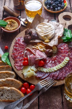 Ahşap tahta üzerinde farklı lezzetli et ve peynir aperatifler.