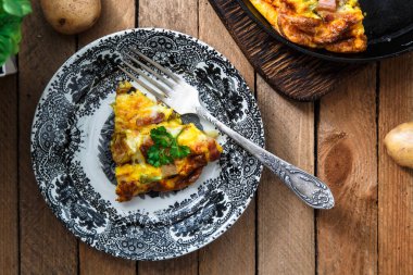 Sosis, patates, pırasa ve peynir bir tabakta üstten görünüm ile omlet