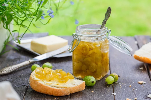 Gröna krusbär jam i en burk på ett träbord — Stockfoto