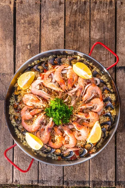 Paella tradicional de frutos do mar na frigideira em uma mesa velha de madeira, vista superior — Fotografia de Stock