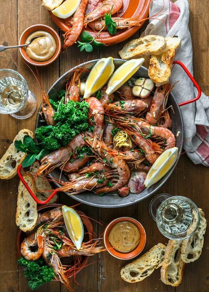 Mesa con muchos platos con camarones, pan, limones y vino, vista superior — Foto de Stock