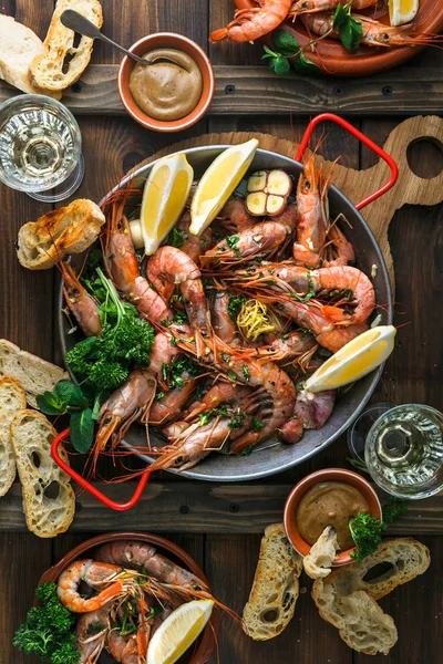 Sartén de paella con camarones tigre asado y muchos platos, pan y vino — Foto de Stock