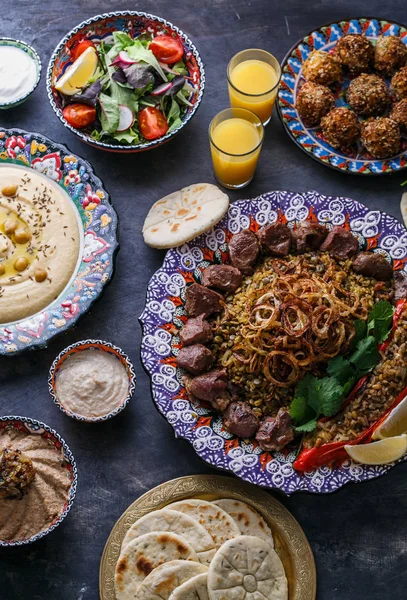 Platos de Oriente Medio o árabe y meze surtidos sobre un fondo oscuro. Carne kebab, falafel, baba ghanoush, hummus, arroz con verduras, tahini, kibbeh, pita. Comida halal. Espacio para el texto. Vista superior —  Fotos de Stock