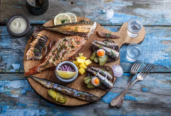 Smoked fish appetizers with mackerel, sturgeon, perch on woden cutting board