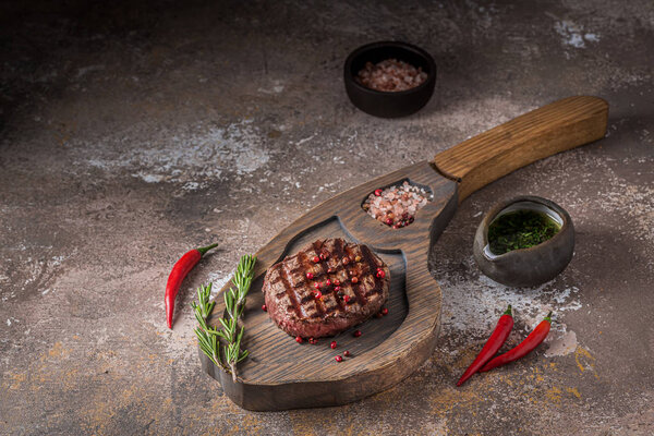 Grilled tenderloin beef steak on wooden board with space for wording