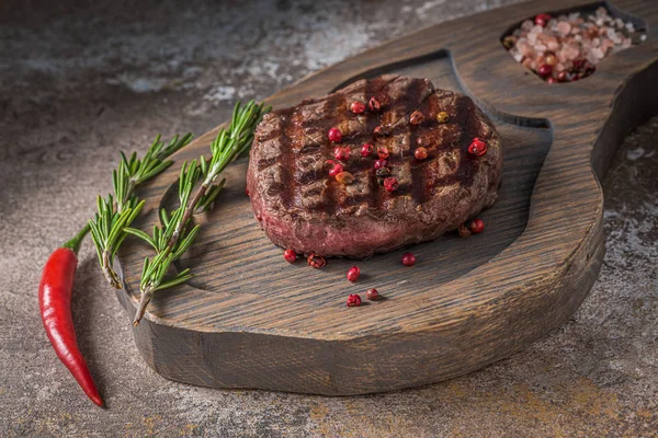 Tendeeloin steak op houten bord met peper en zout van dichtbij bekijken — Stockfoto