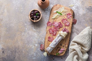 Italian salami on wooden board with cheese and olives