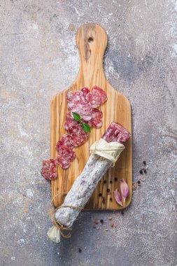 Italian salami on wooden board with cheese and olives