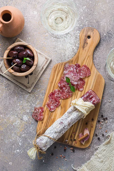 Italiaanse salami op houten plank met kaas en olijven — Stockfoto