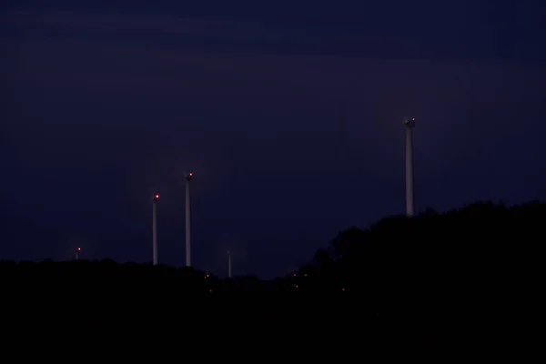 Větrné turbíny za soumraku, čepele vypadají jako kola. — Stock fotografie