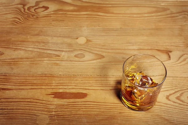 Vaso de whisky con hielo sobre una vieja mesa de madera —  Fotos de Stock