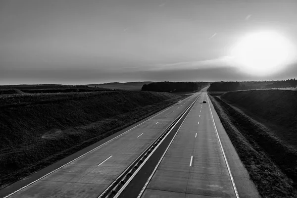 Kraju autostrady i zachód słońca. Jasną drogę Świetne nuture wokół. Blac — Zdjęcie stockowe