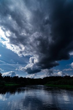 Büyük nehir ve yeşil kıyıları. Bulutlar ve mavi gökyüzü yukarıda. Hala w