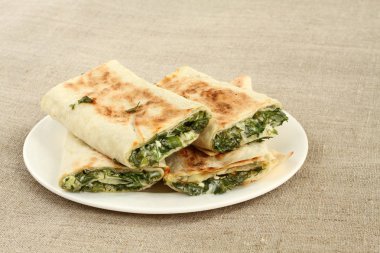 Otlar ve beyaz peynir beyaz plaka kumaş üzerine kavrulmuş rulo ekmek silindir Mini değirmenler dolu
