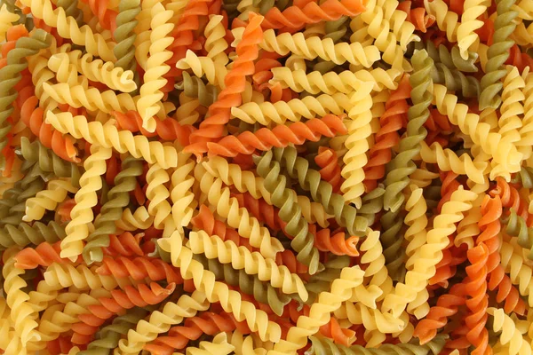 Food background - uncooked three-colored Fusilli durum wheat pasta with spinach and tomato — Stock Photo, Image