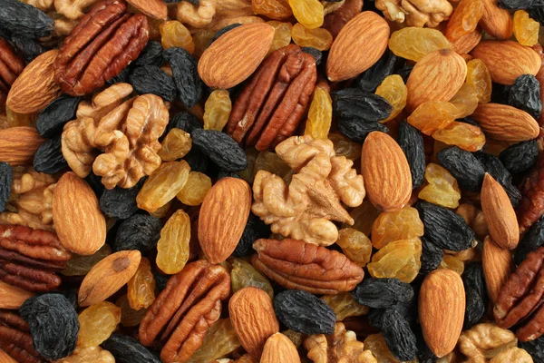 Food background - big peeled almonds, peeled walnuts, peeled pecan nuts, big dark blue raisins and yellow raisins situated arbitrarily