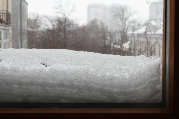 在一个阴云密布的冬日 从房间里可以看到街景 雪粘在窗户的外面 — 图库照片