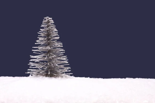 Giocattolo argento albero di Natale su artificiale bianco neve contro blu navy sfondo — Foto Stock