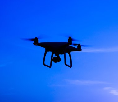 Quadrocopters siluet güneşin arka planı. Akşam gökyüzünde uçan uçaklar.