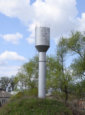 Yeşil çimenler ve ağaçların arasında Gümüş Su Kulesi.