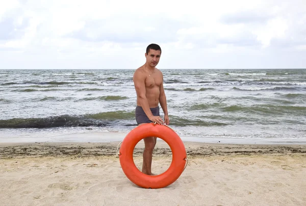 Человек на пляже с спасательным буем — стоковое фото