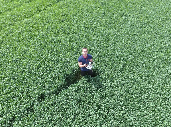 Homem segurando quadricópteros de controle remoto em pé na grama verde no campo — Fotografia de Stock