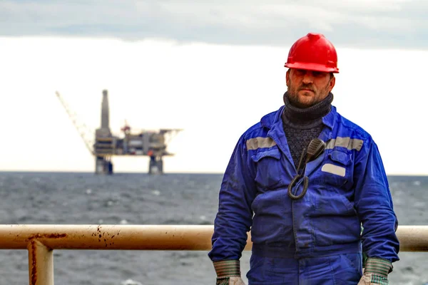 Oilman skiftarbetare på däck på fartyget på bakgrunden offshore olja hylla planforms. Arbeta på sättet att arbeta — Stockfoto