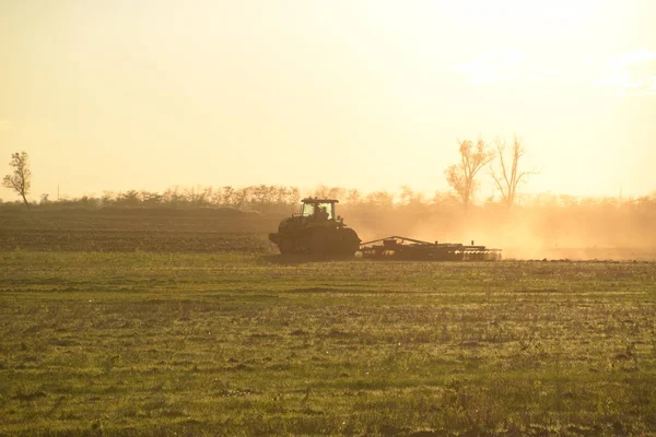 Traktor saat matahari terbenam membajak ladang. Tilling tanah di musim gugur setelah panen. Akhir musim ini — Stok Foto