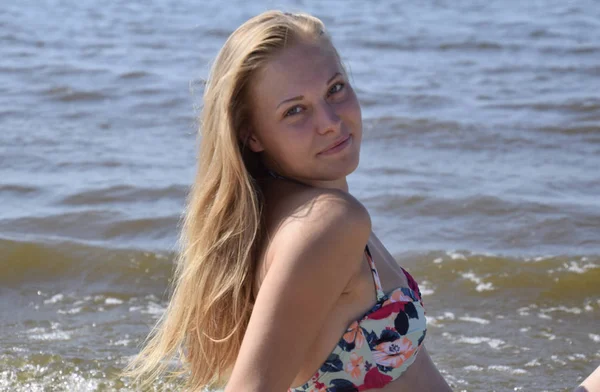 Deniz suyu bir arka plan üzerinde kız sarışın. Renkli bikinili güzel genç kadın