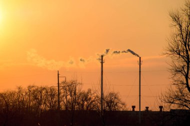 Kazan boruları günbatımında duman. Kış manzarası.