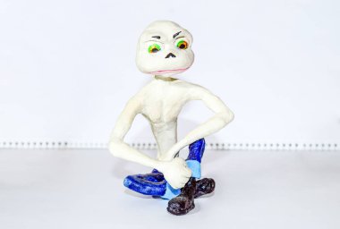 Umorik duruş oturma içinde. Büyük bir kafası sıska bir karakterle heykelcik. Kil ve kil kalıplanmış